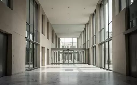 Ein leerer, architektonisch minimalistischer Flur in einem modernen Regierungsgebäude mit hellem Tageslicht auf dem Boden. - Foto: über boerse-global.de