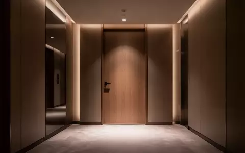 Ein modern gestalteter, leerer Hotelflur mit stimmungsvoller Beleuchtung und minimalistischen HolztĂĽren. - Foto: ĂĽber boerse-global.de