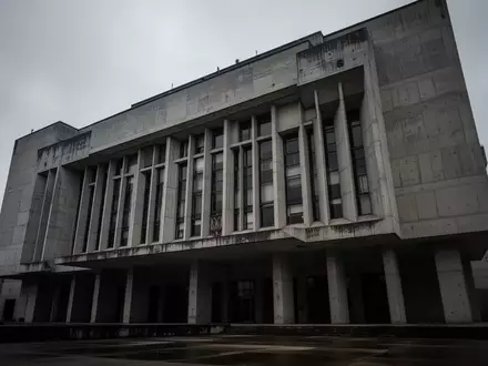 Die Fassade eines massiven, brutalistischen Regierungsgebäudes unter einem grauen Himmel. - Foto: über boerse-global.de