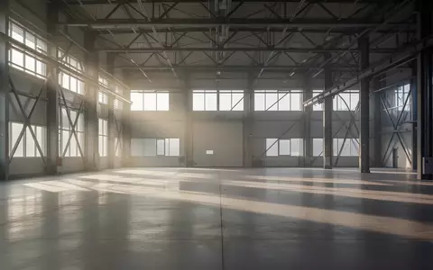 Eine leere, lichtdurchflutete Industriehalle mit Stahlträgern und Betonboden als Symbol für die deutsche Wirtschaftslage. - Foto: über boerse-global.de