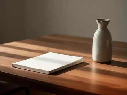 Ein minimalistischer, leerer Schreibtisch mit einem geschlossenen Notizbuch und einer Wasserkaraffe im sanften Tageslicht. - Foto: über boerse-global.de