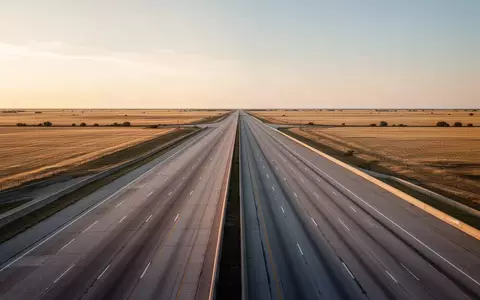 Eine weitläufige, leere Autobahn in der texanischen Landschaft bei Dämmerung. - Foto: über boerse-global.de