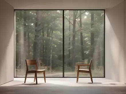 Ein minimalistisch eingerichteter, sonnendurchfluteter Raum mit einem leeren Stuhl vor einem Fenster mit Blick auf einen Wald. - Foto: über boerse-global.de