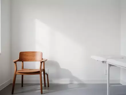 Ein leerer, minimalistischer Behandlungsraum in einer Arztpraxis mit einem Stuhl und hellem Tageslicht. - Foto: über boerse-global.de