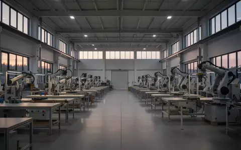 Eine leere, moderne Industriehalle mit stillstehenden Maschinen und natürlichem Lichteinfall. - Foto: über boerse-global.de