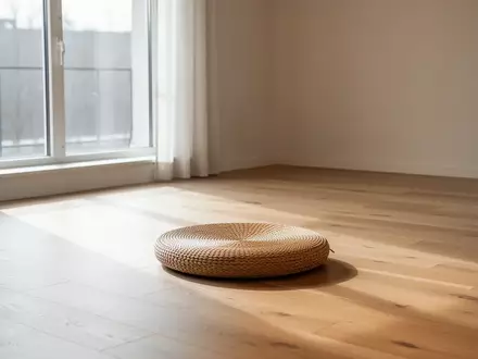 Ein minimalistischer, lichtdurchfluteter Raum mit einem einzelnen Meditationskissen auf einem Holzboden. - Foto: über boerse-global.de