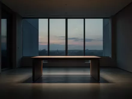 Ein minimalistischer, leerer Arbeitsbereich in einem modernen Raum bei Dämmerung, der eine Atmosphäre von Distanz und Stille vermittelt. - Foto: über boerse-global.de