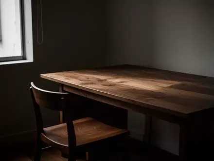 Ein minimalistisch eingerichtetes Heimbüro mit einem leeren Schreibtisch und Stuhl in gedämpftem Tageslicht. - Foto: über boerse-global.de