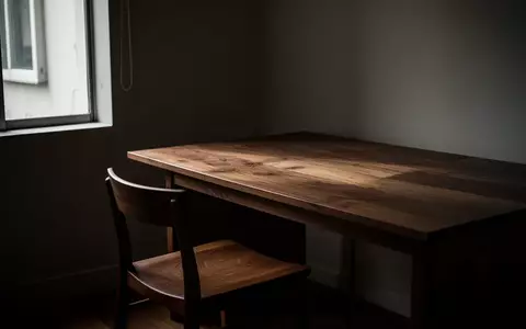Ein minimalistisch eingerichtetes Heimbüro mit einem leeren Schreibtisch und Stuhl in gedämpftem Tageslicht. - Foto: über boerse-global.de