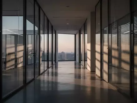 Ein minimalistischer, moderner Büroflur mit Glaswänden und polierten Betonböden in der Abenddämmerung. - Foto: über boerse-global.de
