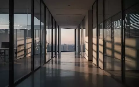 Ein minimalistischer, moderner Büroflur mit Glaswänden und polierten Betonböden in der Abenddämmerung. - Foto: über boerse-global.de