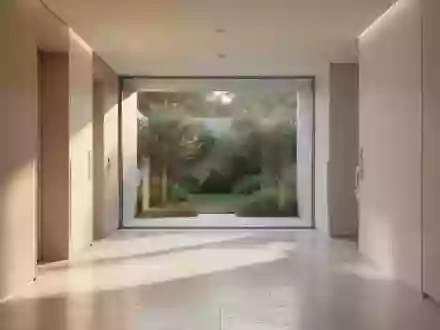Ein minimalistischer Flur in einer modernen medizinischen Einrichtung mit hellem Steinboden und Blick in einen grünen Innenhof. - Foto: über boerse-global.de