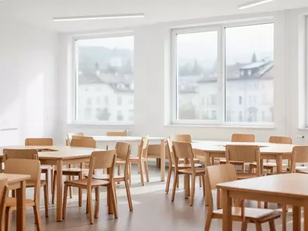 Ein heller, moderner Unterrichtsraum mit minimalistischer Einrichtung und natürlichem Tageslicht in einem Gebäude in Linz. - Foto: über boerse-global.de
