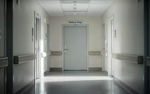 Ein leerer, heller Krankenhausflur mit glänzendem Boden und einer geschlossenen Tür in einer sterilen Umgebung. - Foto: über boerse-global.de