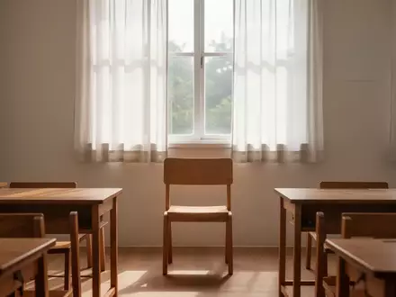 Ein ruhiger, sonnendurchfluteter Klassenraum mit minimalistischen Holzmöbeln und einem leeren Stuhl vor einem Fenster. - Foto: über boerse-global.de