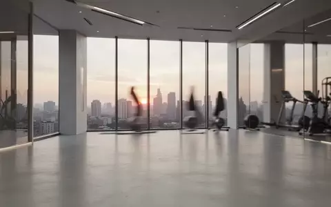 Modernes, minimalistisches Fitnessstudio mit groĂen Fenstern und Blick auf die Stadt bei Sonnenuntergang. - Foto: ĂŒber boerse-global.de