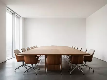 Ein minimalistischer, leerer Konferenzraum mit einem Holztisch und Tageslicht, der eine ruhige und strukturierte Arbeitsumgebung vermittelt. - Foto: über boerse-global.de