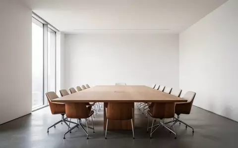 Ein minimalistischer, leerer Konferenzraum mit einem Holztisch und Tageslicht, der eine ruhige und strukturierte Arbeitsumgebung vermittelt. - Foto: über boerse-global.de