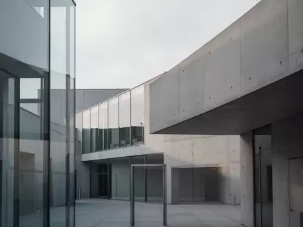 Moderne architektonische Fassade eines Behördengebäudes mit klaren Linien und geometrischen Formen bei Tageslicht. - Foto: über boerse-global.de