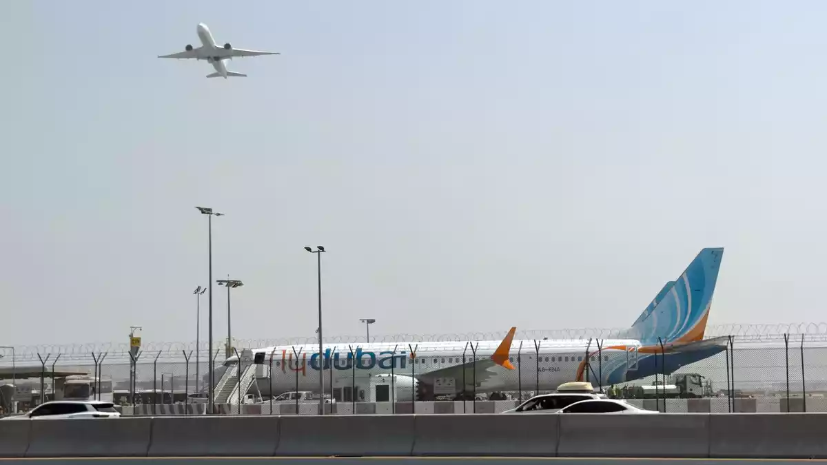 Ein Flugzeug hebt ab, während ein Flydubai-Flieger in Dubai auf dem Flughafen steht.  - Bild: Uncredited/AP/dpa