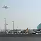 Ein Flugzeug hebt ab, während ein Flydubai-Flieger in Dubai auf dem Flughafen steht.  - Bild: Uncredited/AP/dpa