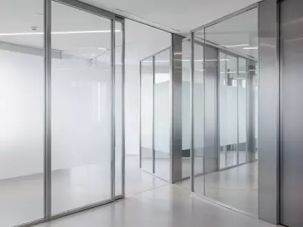 Ein minimalistischer, moderner Büroflur mit klaren Glaspaneelen und Metalltrennwänden in neutralem, professionellem Licht. - Foto: über boerse-global.de