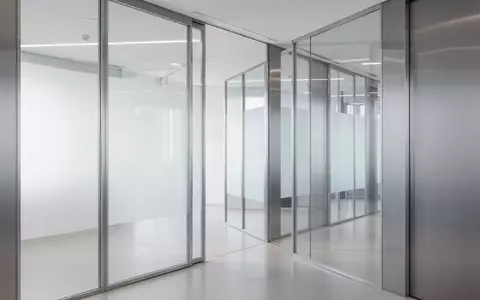 Ein minimalistischer, moderner Büroflur mit klaren Glaspaneelen und Metalltrennwänden in neutralem, professionellem Licht. - Foto: über boerse-global.de