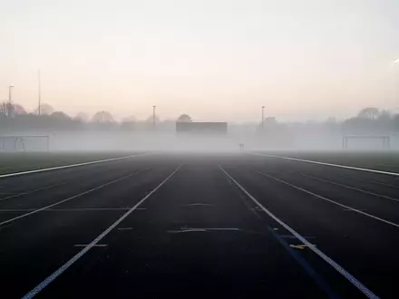 Eine leere Laufbahn in den frühen Morgenstunden bei Nebel, die eine ruhige und motivierende Atmosphäre vermittelt. - Foto: über boerse-global.de