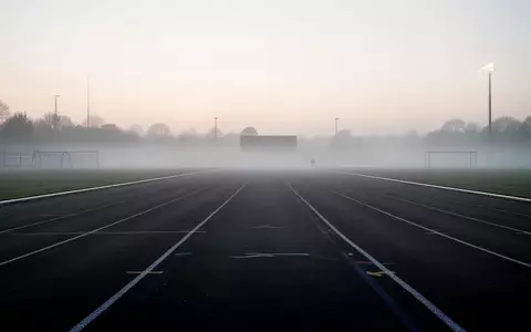 Eine leere Laufbahn in den frühen Morgenstunden bei Nebel, die eine ruhige und motivierende Atmosphäre vermittelt. - Foto: über boerse-global.de