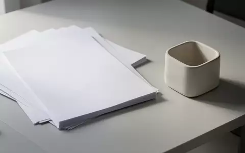 Ein minimalistischer, aufgeräumter Schreibtisch mit weißem Papier und einem leeren Stiftehalter bei sanftem Tageslicht. - Foto: über boerse-global.de