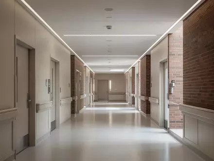 Ein minimalistischer, heller Krankenhausflur in einem modernen Backsteingebäude mit neutralen Wänden und glattem Boden. - Foto: über boerse-global.de