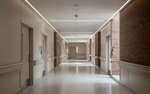 Ein minimalistischer, heller Krankenhausflur in einem modernen Backsteingebäude mit neutralen Wänden und glattem Boden. - Foto: über boerse-global.de