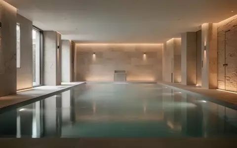 Ein ruhiges, modernes Thermalbad mit sanfter Beleuchtung und spiegelnder Wasseroberfläche in einer minimalistischen Architektur. - Foto: über boerse-global.de