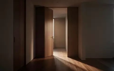 Ein minimalistischer, unmöblierter Flur in einer Wohnung mit einer leicht geöffneten Holztür und sanftem Lichteinfall. - Foto: über boerse-global.de