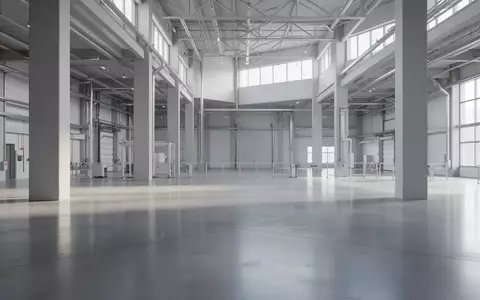 Ein weitläufiges, leeres Industriegebäude mit poliertem Betonboden und minimalistischen Säulen bei natürlichem Tageslicht. - Foto: über boerse-global.de