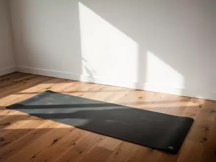 Ein minimalistischer, lichtdurchfluteter Trainingsbereich in einem Raum mit Holzboden und einer ausgerollten Yogamatte. - Foto: über boerse-global.de