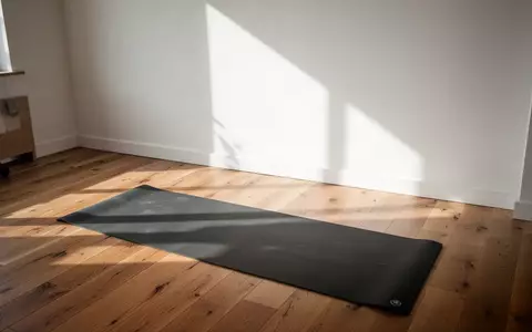Ein minimalistischer, lichtdurchfluteter Trainingsbereich in einem Raum mit Holzboden und einer ausgerollten Yogamatte. - Foto: über boerse-global.de