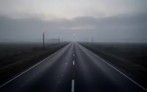 Eine leere, verlassene Asphaltstraße erstreckt sich in den nebligen Horizont bei Dämmerung. - Foto: über boerse-global.de