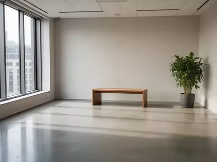 Ein minimalistisches, helles Bürointerieur mit poliertem Betonboden und einer einzelnen Pflanze. - Foto: über boerse-global.de