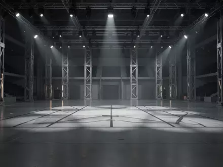 Eine leere, modern beleuchtete Arena mit poliertem Betonboden und industrieller Architektur für ein Robotik-Testevent. - Foto: über boerse-global.de