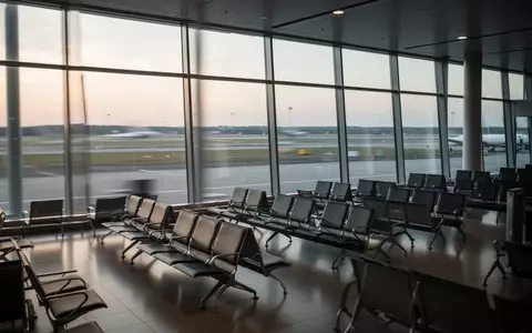 Leere Sitzreihen in einem modernen Flughafen-Terminal vor einer großen Fensterfront bei Morgenlicht. - Foto: über boerse-global.de