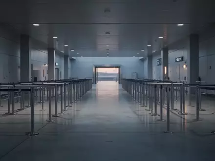 Eine leere, minimalistische Ankunftshalle an einem internationalen Flughafen mit glatten Bodenflächen und Sicherheitsbarrieren. - Foto: über boerse-global.de