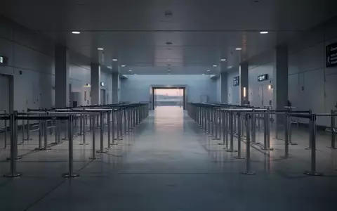Eine leere, minimalistische Ankunftshalle an einem internationalen Flughafen mit glatten Bodenflächen und Sicherheitsbarrieren. - Foto: über boerse-global.de