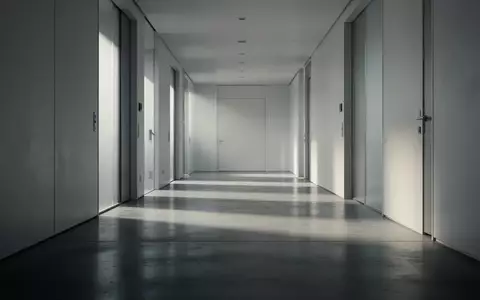 Ein minimalistischer, leerer Flur mit poliertem Betonboden und weichem Lichteinfall, der eine Atmosphäre von Vorsicht und Vertrauen vermittelt. - Foto: über boerse-global.de