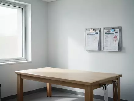 Ein minimalistischer, heller Behandlungsraum in einer Arztpraxis mit einer Untersuchungsliege und neutraler Einrichtung. - Foto: über boerse-global.de