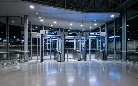 Ein moderner, menschenleerer Grenzübergang an einem Flughafen mit architektonischen Linien und blauer Beleuchtung. - Foto: über boerse-global.de