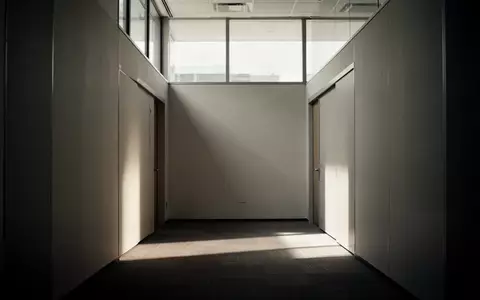 Ein leerer, in gedämpftes Licht getauchter Flur in einem Bürogebäude, der eine Atmosphäre der Stille und Leere vermittelt. - Foto: über boerse-global.de
