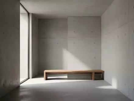 Ein minimalistischer, moderner Innenraum mit schlichten Betonwänden und weichem Tageslicht auf einer leeren Holzbank. - Foto: über boerse-global.de