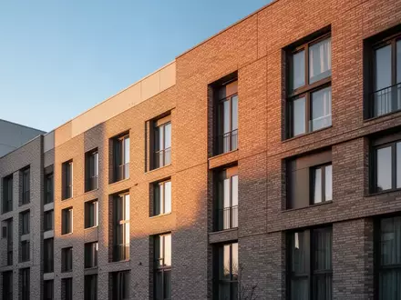 Moderne Wohnhausfassade im warmen Licht der Abendsonne als Symbol für den Ausbau privater Energieerzeugung. - Foto: über boerse-global.de