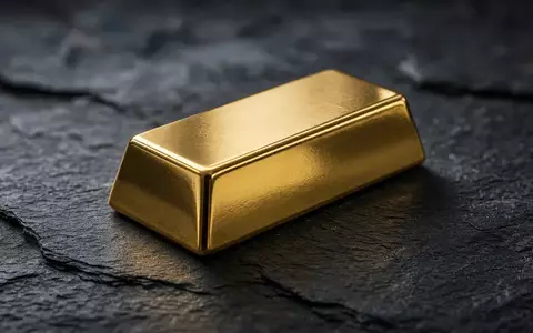 Ein einzelner Goldbarren auf einer dunklen Schieferplatte bei gedämpftem, natürlichem Licht. - Foto: über boerse-global.de